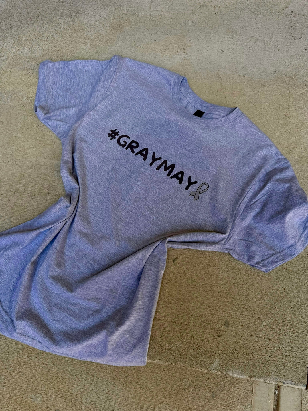 Gray t-shirt with '#GRAYMAY' text on a beige surface