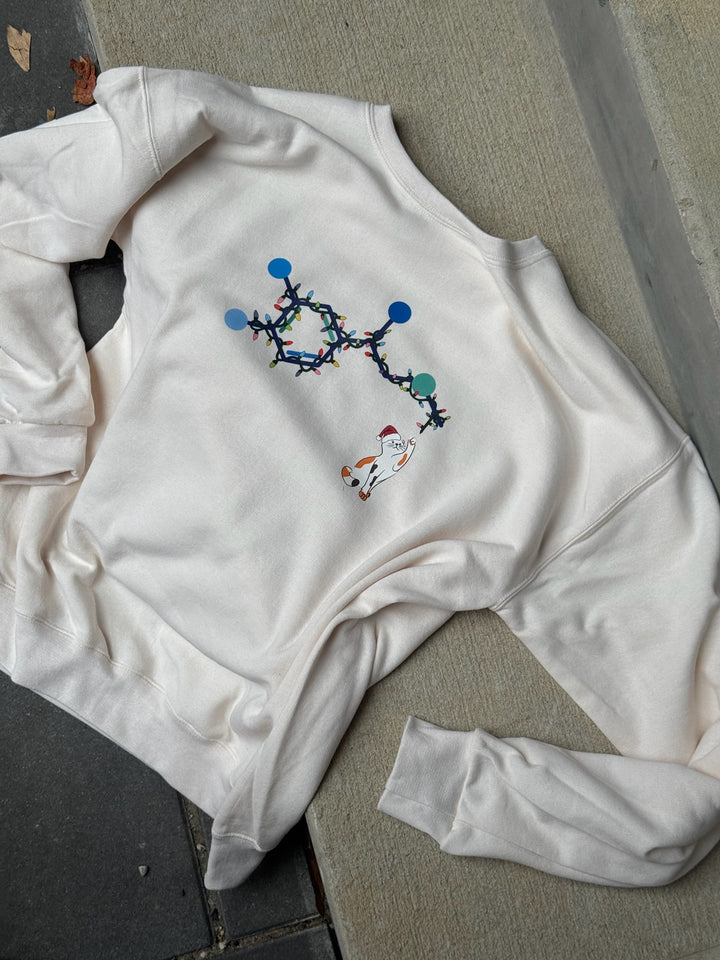 White sweatshirt with colorful molecular adrenaline holiday cat design on a gray surface