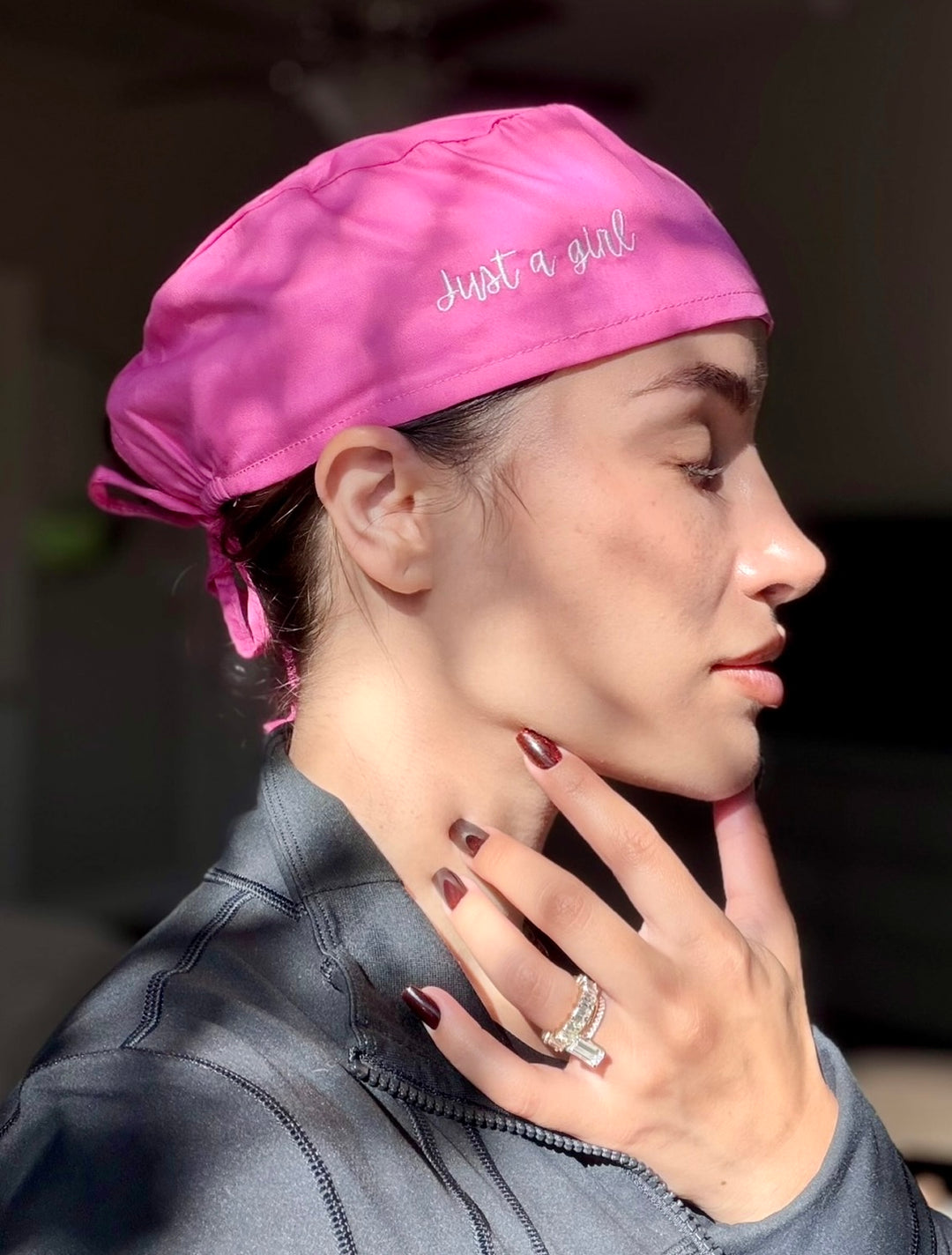 Dr. Daisy wearing a pink scrub cap with 'Just a Girl' text, looking away from the camera.