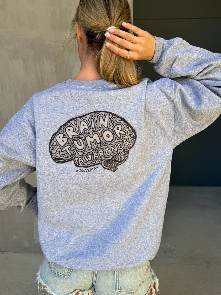Person wearing a gray sweatshirt with 'Brain Tumor Awareness' design on the back.