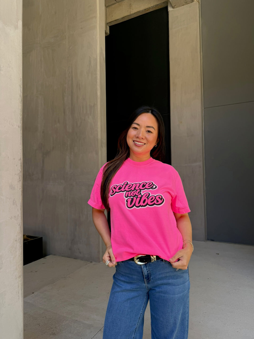 Person wearing a pink t-shirt with Science, not vibes text standing in a doorway.