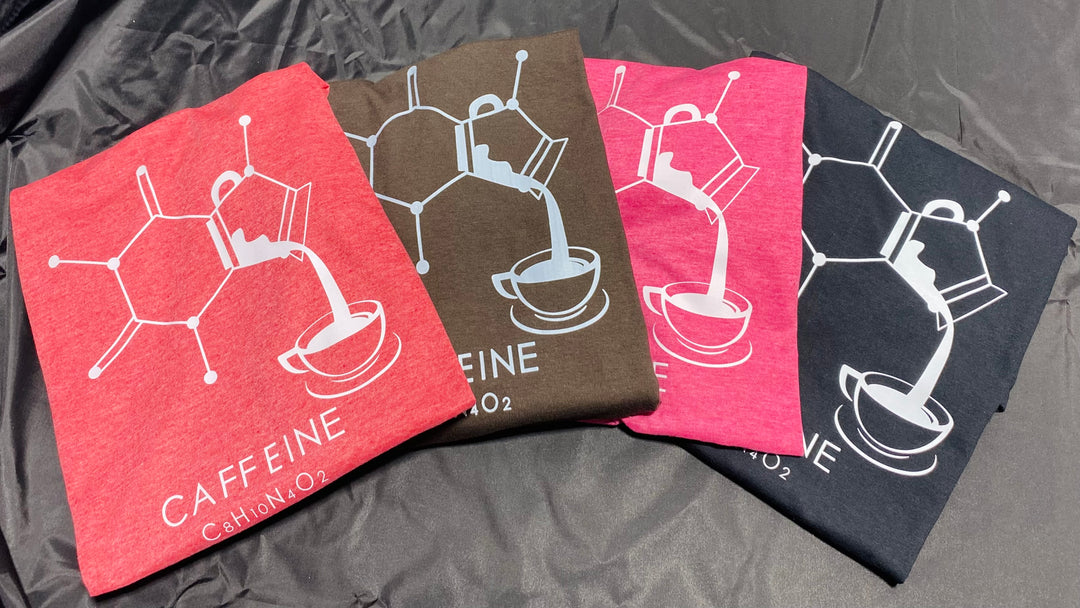 Four Enerjava t-shirts with caffeine molecule designs on a dark fabric background