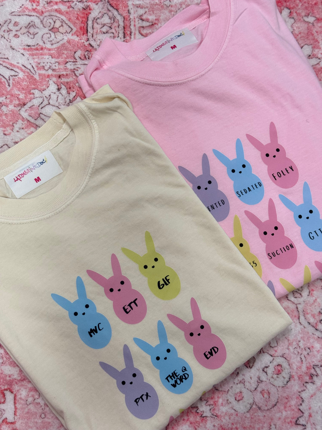 Folded  Trauma Squad and ICU Squad tee shirts with pastel bunny designs.