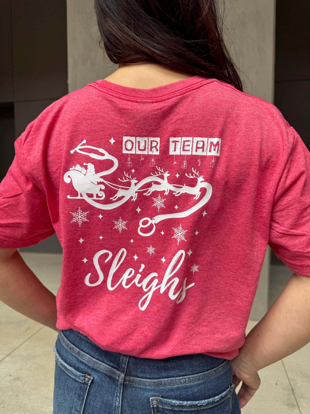 Person wearing a red t-shirt with 'Our Team Sleighs' design on the back.
