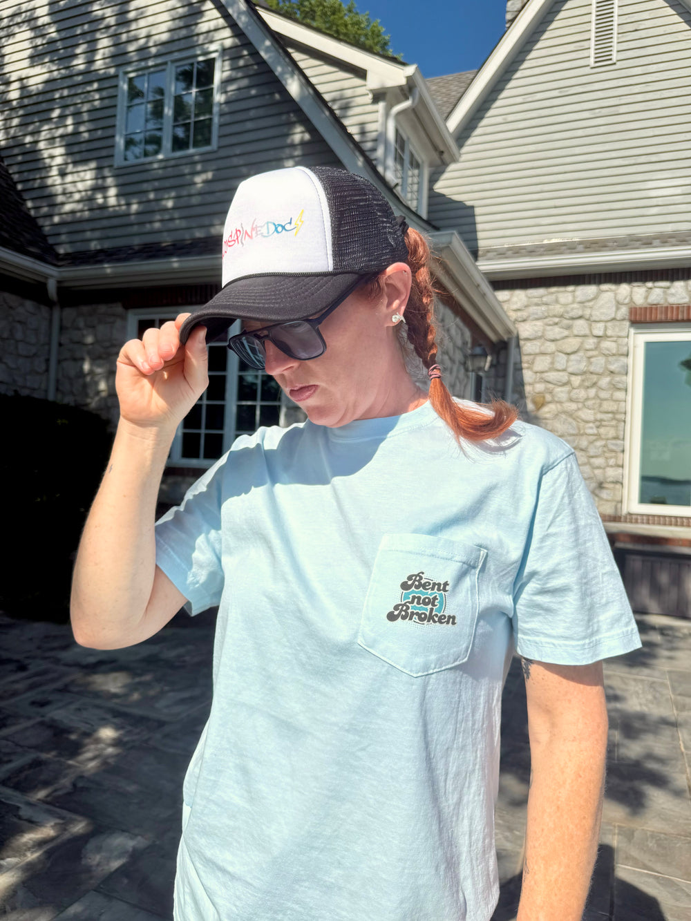 Dr Betsy Grunch wearing the Bent, Not Broken Scoliosis Awareness Tee - Blue Cotton T-Shirt along with a Ladyspinedoc ball cap.