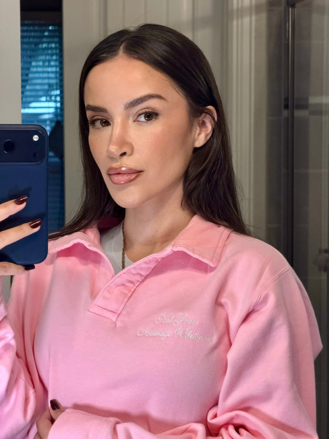 Dr. Daisy wearing Embroidered 'Not Your Average Whitecoat' - Pink Polo Collar Sweatshirt taking a selfie