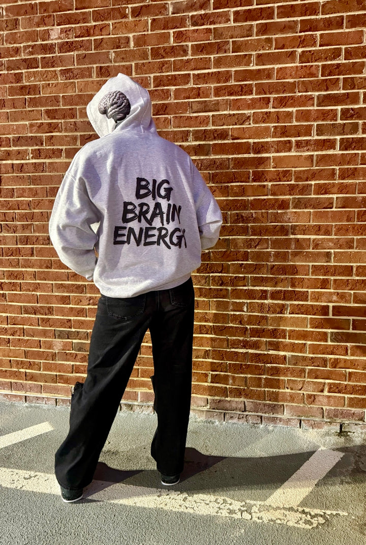 Dr. Betsy Grunch - Ladyspinedoc wearing a light gray hoodie that says "BIG BRAIN ENERGY" in bold black capital letters on the back. The hood is up and shows the brain design on the left side.
