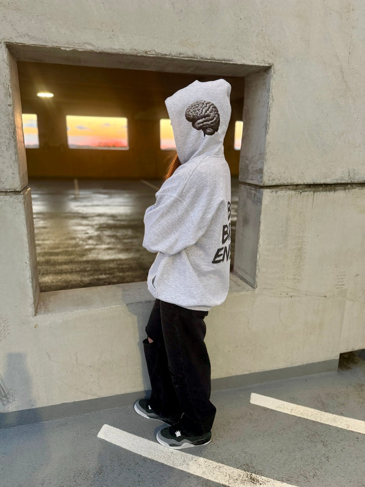 Dr. Betsy Grunch - Ladyspinedoc wearing the BIG BRAIN ENERGY light gray hoodie with the hood up, showcasing the brain design on the left side of the hood.
