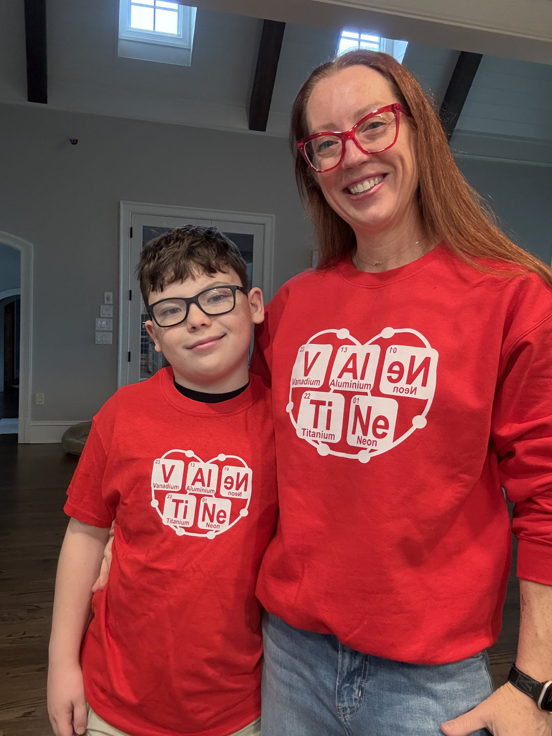 Dr. Betsy Grunch wearing the red Atomic Attraction crewneck sweatshirt with her son wearing the matching Atomic Attraction youth tee shirt

