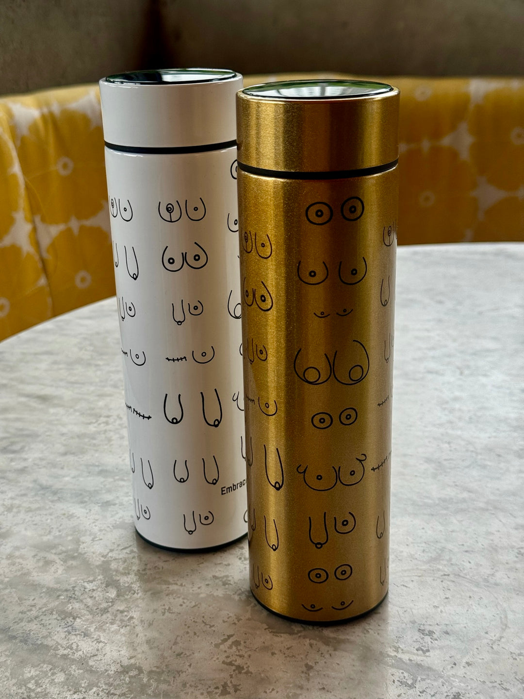 White and Gold Bosom Smart Water Bottles with Breast Design on table
