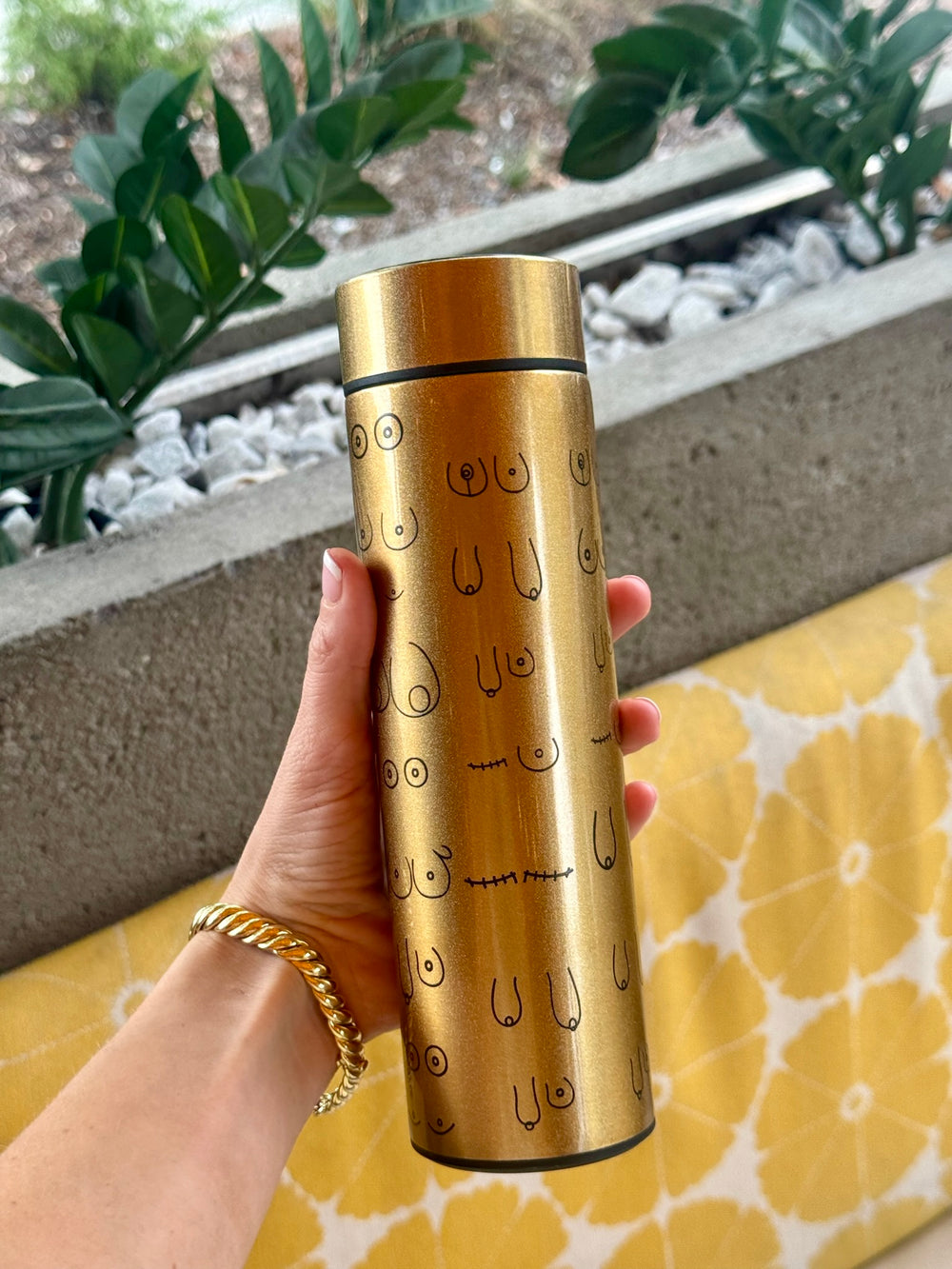 Person holding gold Bosom Smart Water Bottle with Breast Design and LED Temperature Display