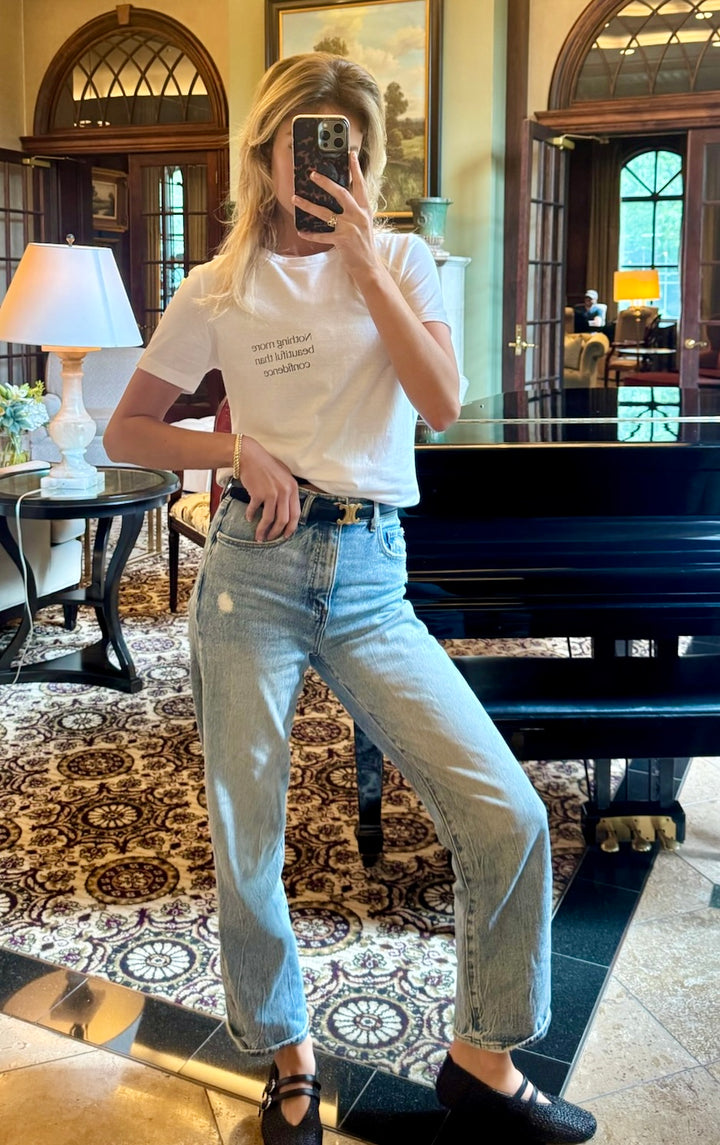 Model wearing The Confidence Doc Confidence Tee Shirt in a formal living room with piano in background