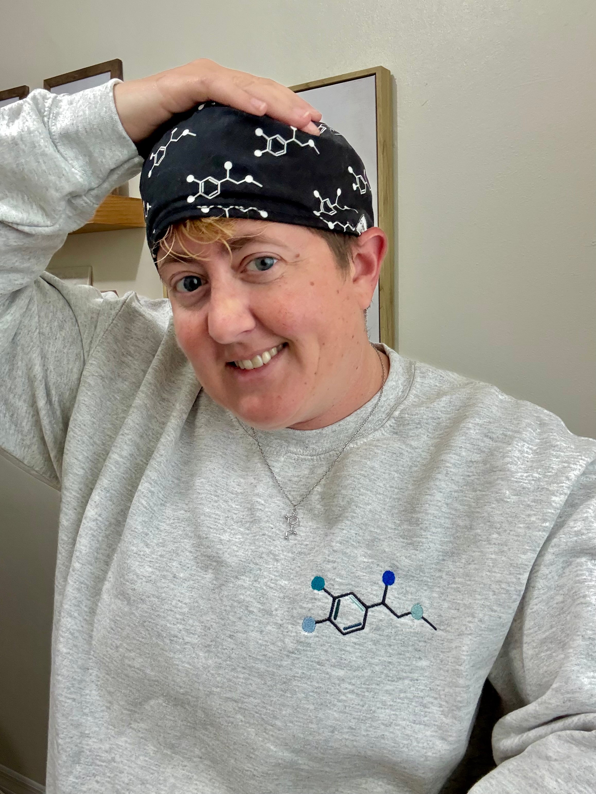 Dr Beachgem wearing Ladyspinedoc x Dr. Beachgem Code Cart Crewneck Sweatshirt - Gray Shirt with Embroidered Epinephrine (Adrenaline) Molecule Design, Noradrenaline necklace, and Code Cart Scrub Cap.
