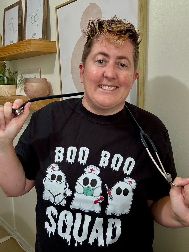 Dr. Beachgem holding a stethoscope and wearing the black Boo Boo Squad Tee Shirt with ghost nurses 