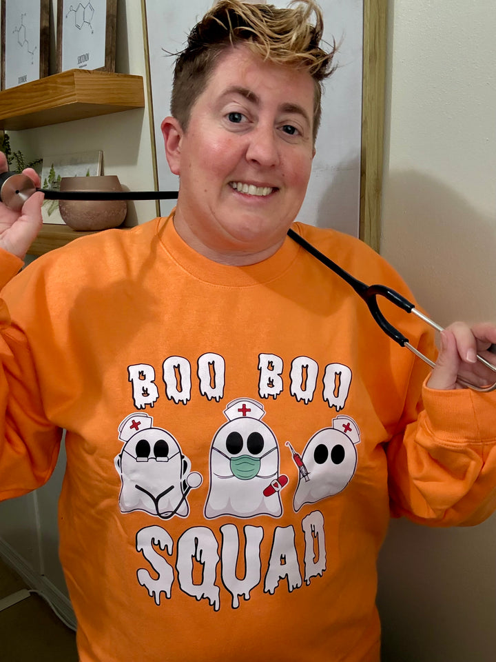Dr. Beachgem holding a stethoscope and wearing the orange Boo Boo Squad Crewneck Sweatshirt with ghost nurses