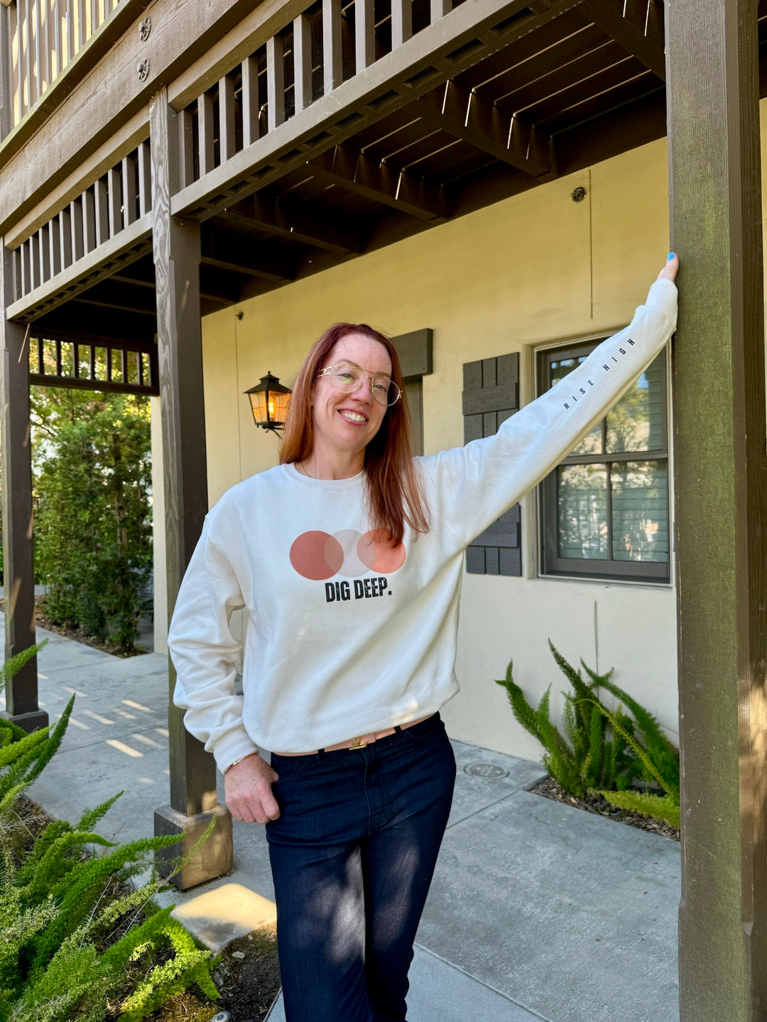 Ladyspinedoc wearing a cream Dig Deep. Rise High sweatshirt, standing outside a building.