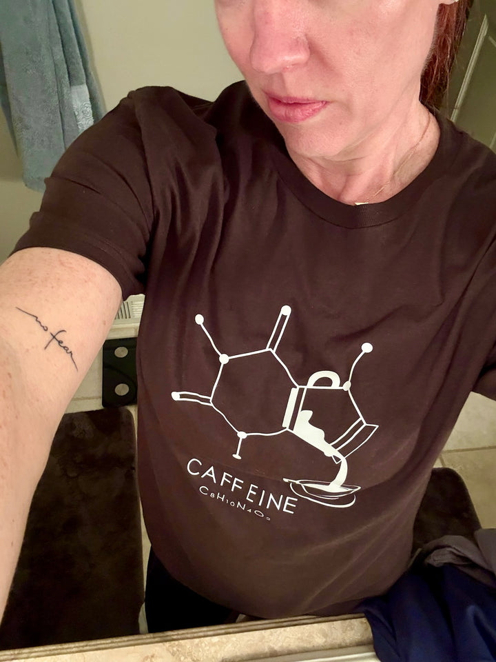 Dr. Betsy Grunch (Ladyspinedoc) wearing a brown Enerjava t-shirt with a caffeine molecule design.