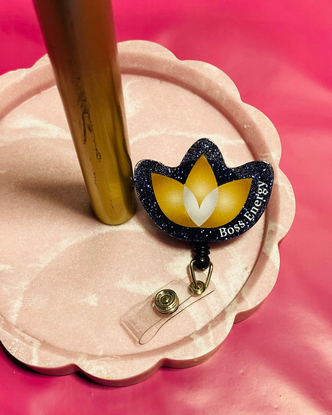 Decorative badge holder with a yellow flower design on a pink stand against a pink background