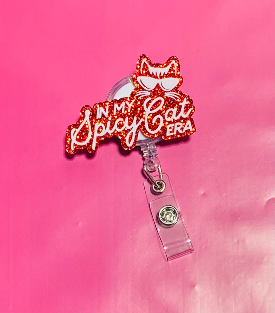 Red glittery badge holder with 'In My Spicy Cat Era' text on a pink background