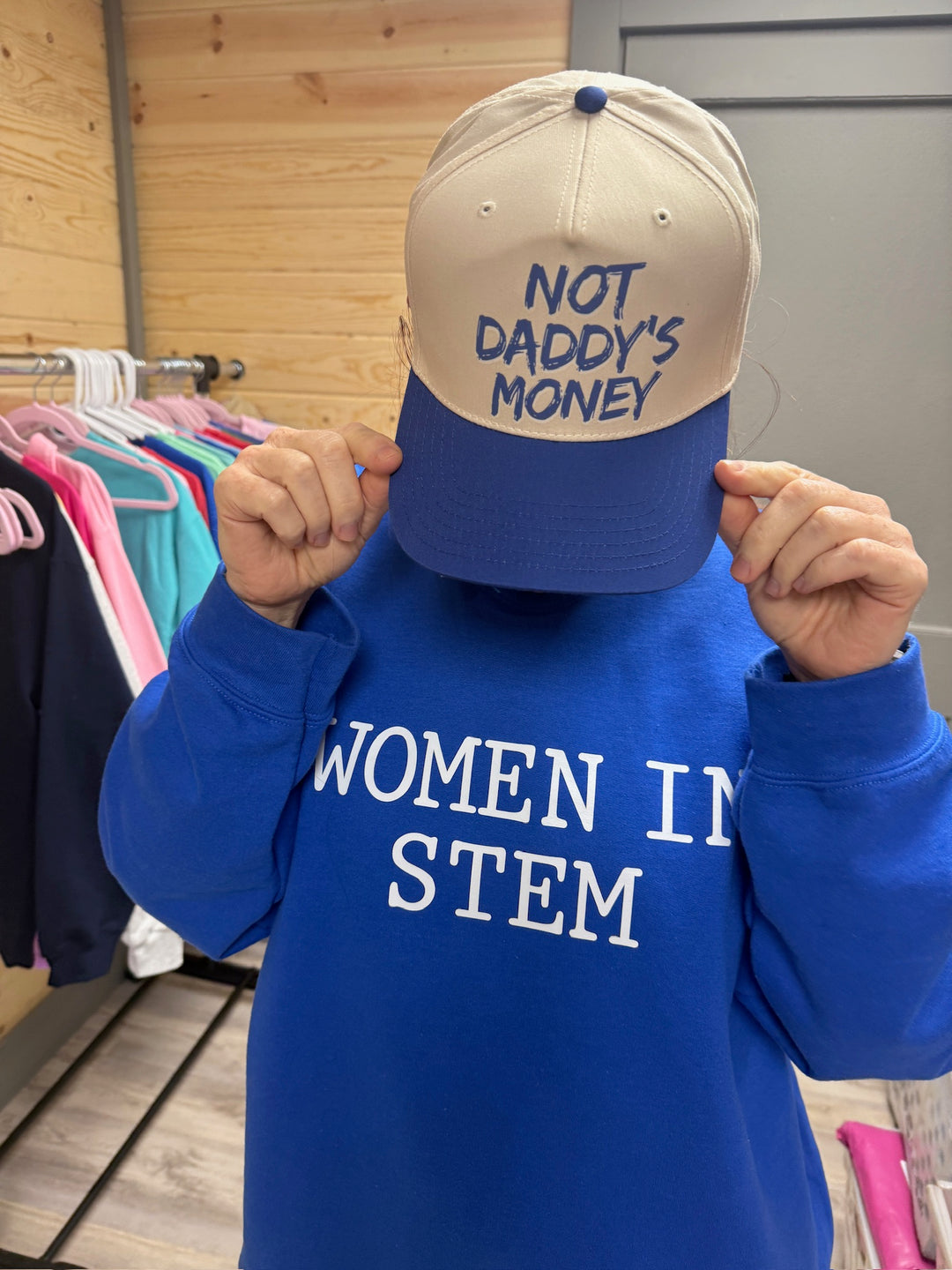 Ladyspinedoc wearing a blue 'Women in STEM' sweatshirt and beige and blue cap "Not Daddy's Money" ball cap.