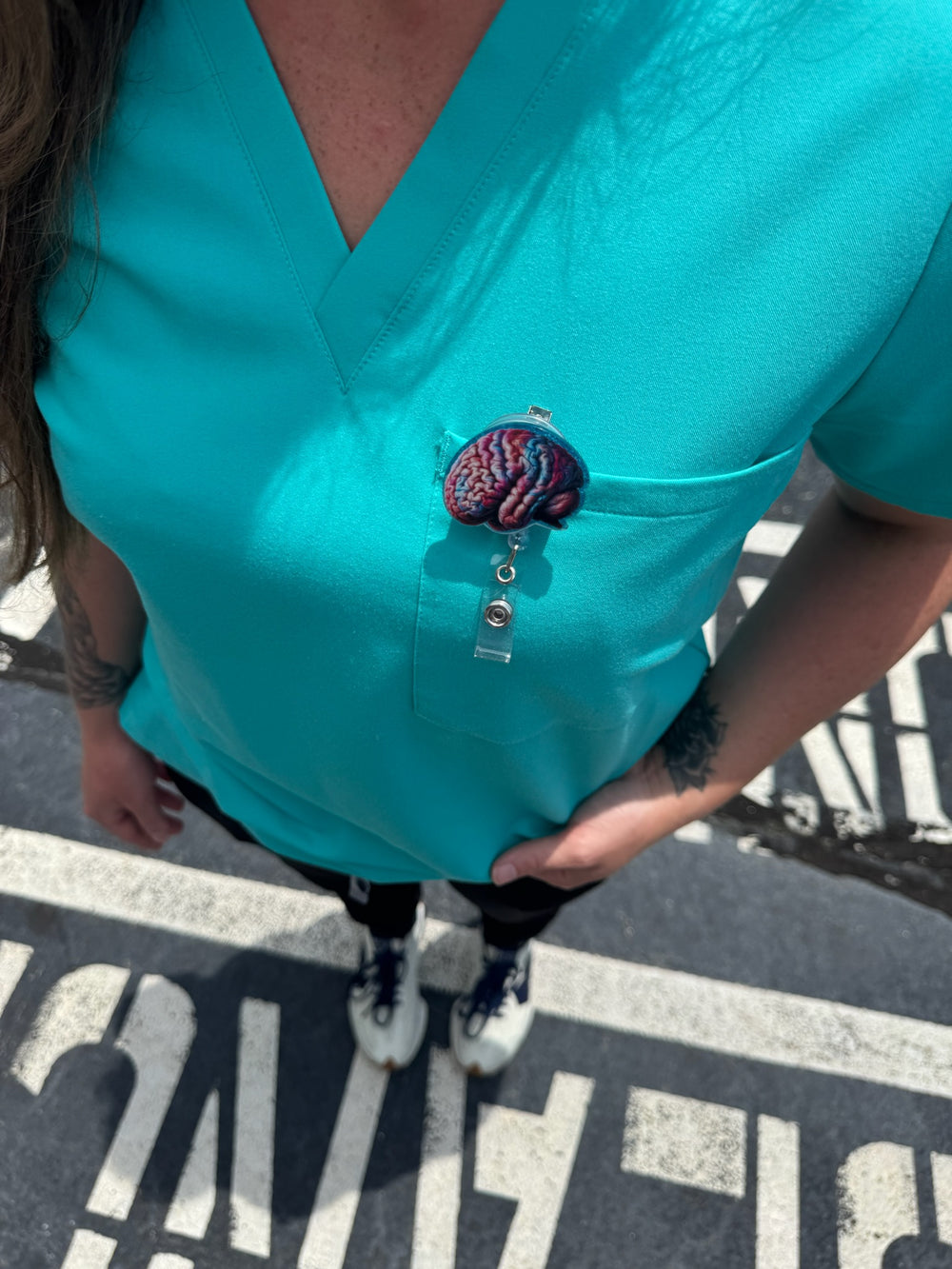 Colorful Brain Badge Reel clipped to woman's front pocket on scrub shirt