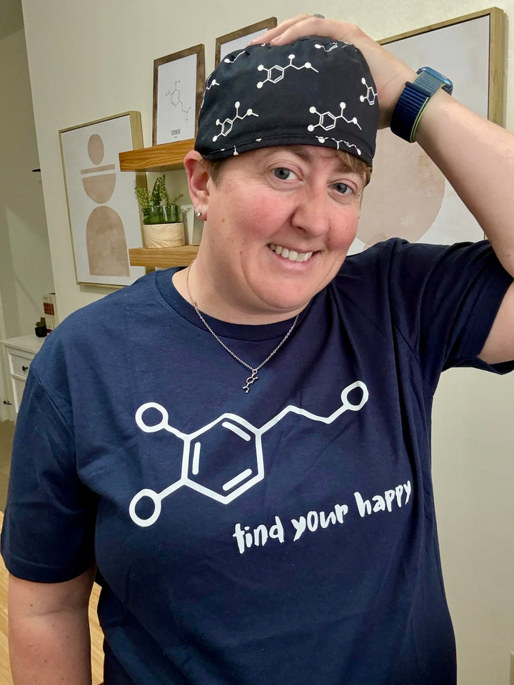 Dr. Beachgem with hand on scrub hat wearing navy Dopamine Rush tee with Dopamine Molecule Design and "Find Your Happy" Motto