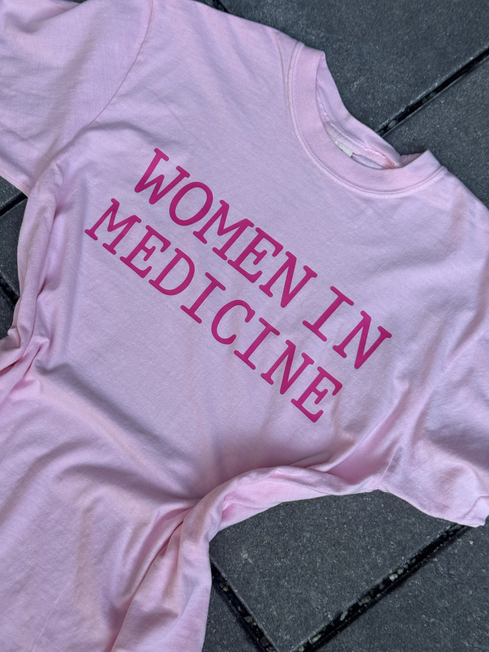 Flay lay of pink Women in Medicine Tee Shirt - Empowering Short Sleeve T-Shirt for Healthcare Pros