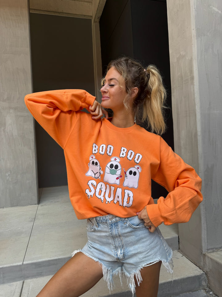 Smiling model wearing cut offs and Ladyspinedoc x Dr. Beachgem Collab: Boo Boo Squad Crewneck Sweatshirt – Halloween Shirt for Healthcare Heroes with ghost nurses