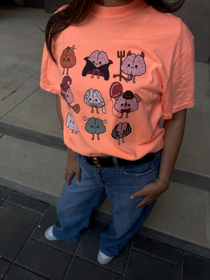 Close up of Model wearing orange Halloween Brains Tee Shirt with Cartoon Brain Characters: Pumpkin, Ghost, Witch, Vampire, Mummy & More
