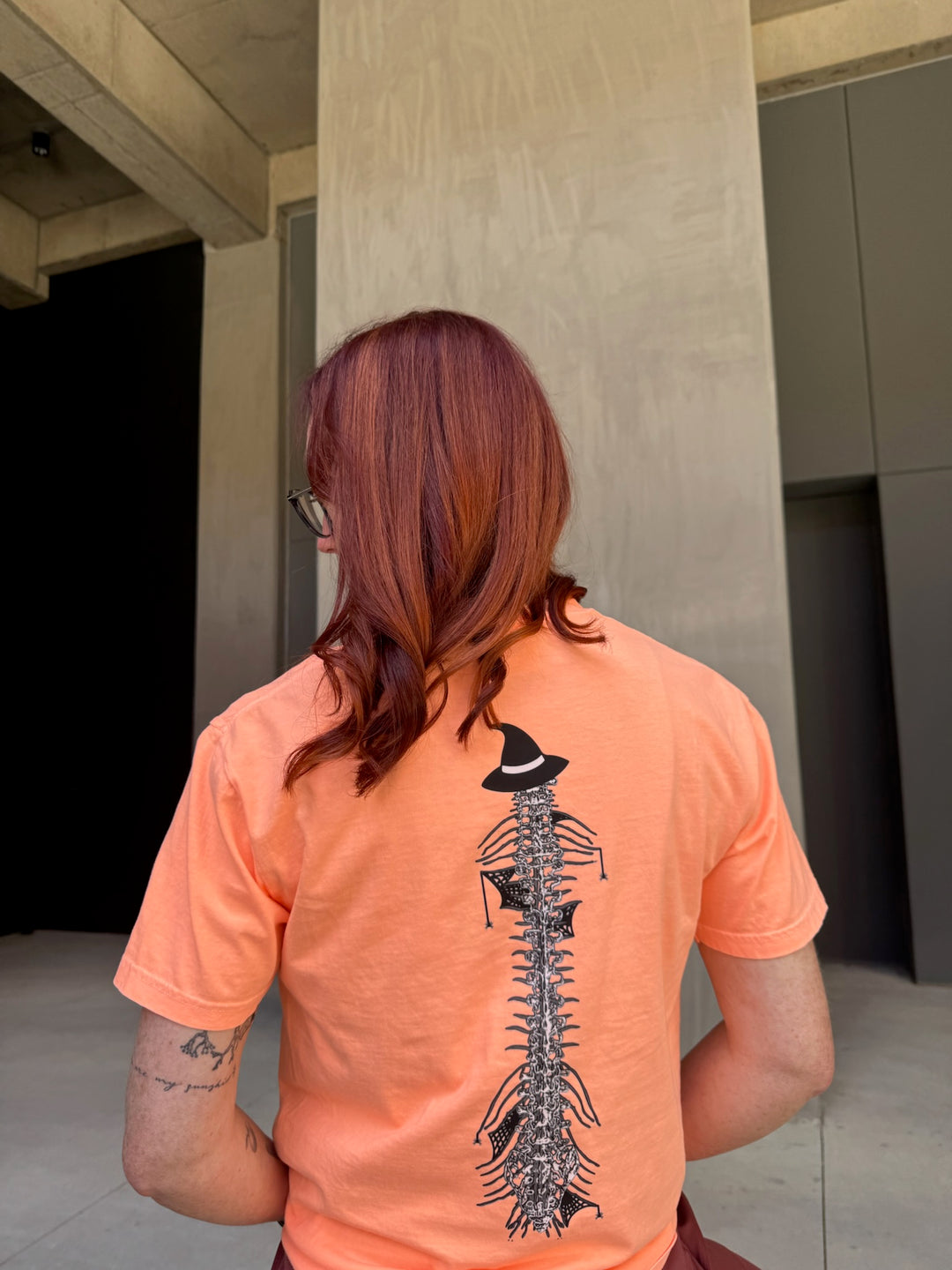 Ladyspinedoc wearing Halloween Spooky Spine - Orange Short Sleeve Tee Shirt and showing off the back spine design