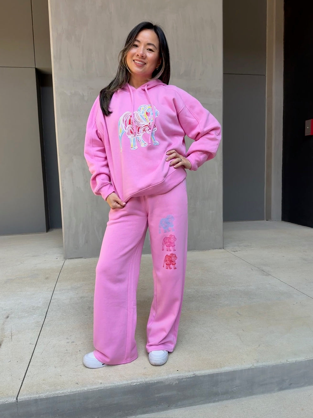 Model showing off the front of the Chan Art Collab: Game Day Set - Pink Hoodie & Sweatpants with colorful bulldogs
