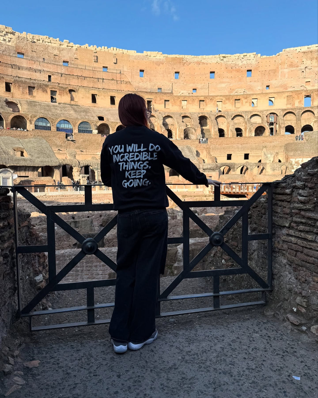 Dr. Betsy Grunch (Ladyspinedoc) facing The Colosseum in Rome Italy and showing the back of the Incredible Sweatshirt with the "YOU WILL DO INCREDIBLE THINGS. KEEP GOING." motto 