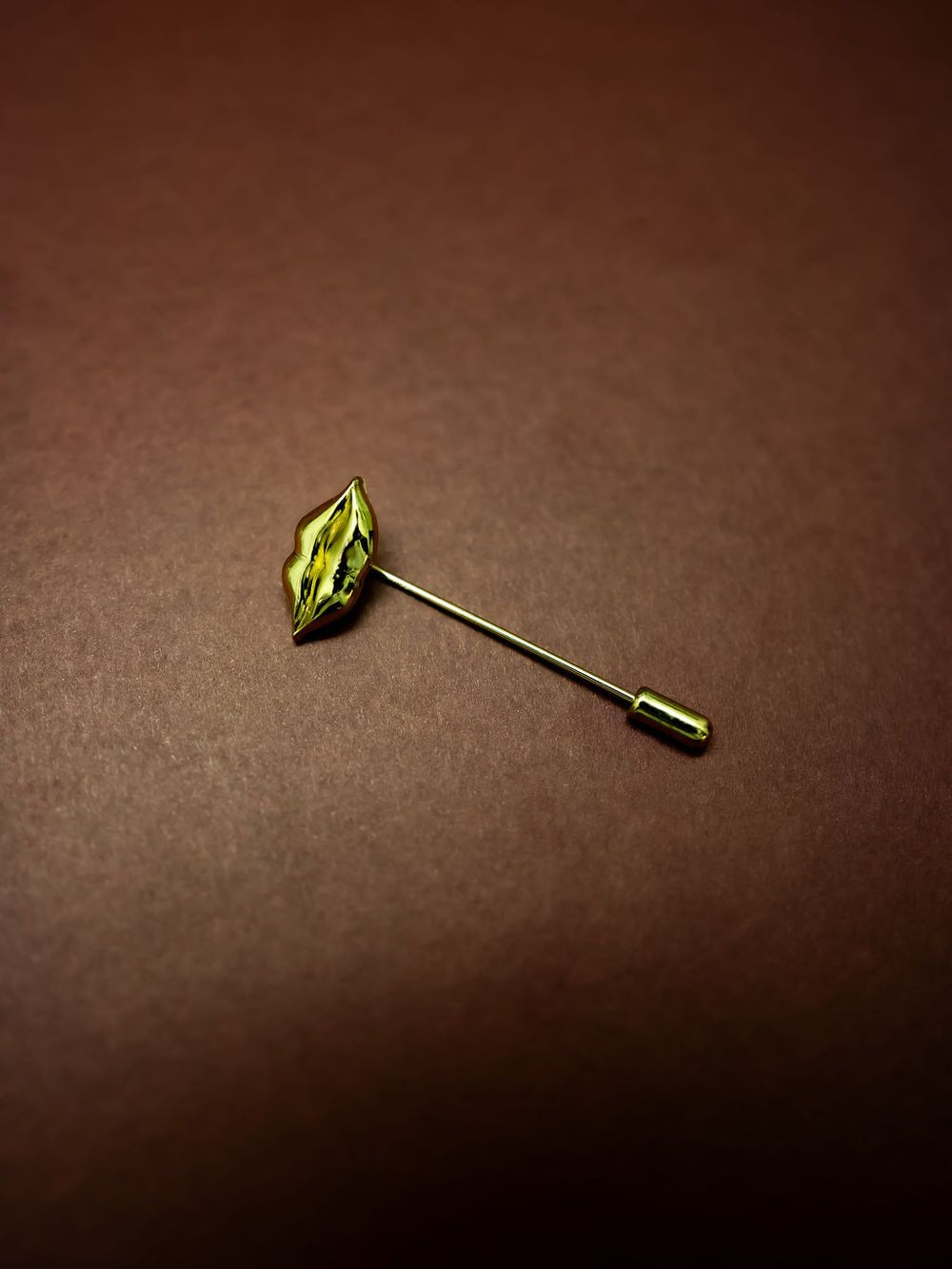 Lips Stick Pin in gold on a burgundy background