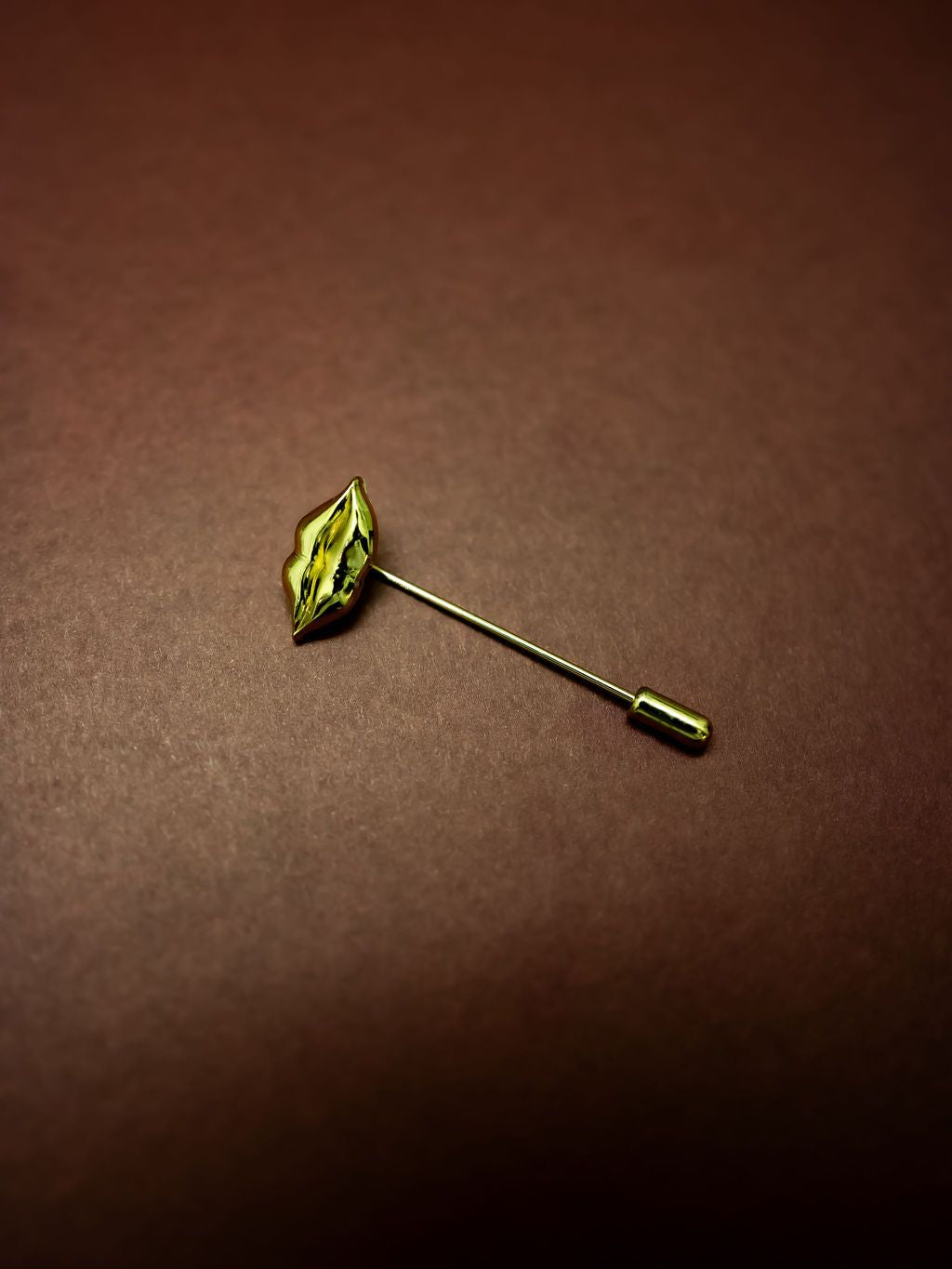 Lips Stick Pin in gold on a burgundy background